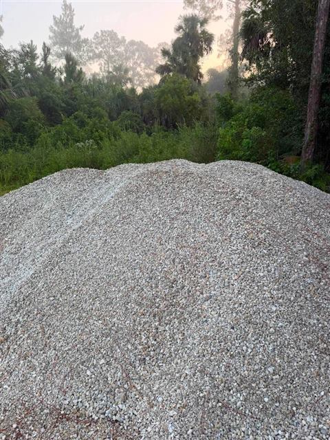 Load of washed limestone gravel delivered to a wooded lot at sunrise