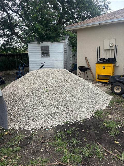 Load of white limestone gravel delivered to a backyard beside a shed