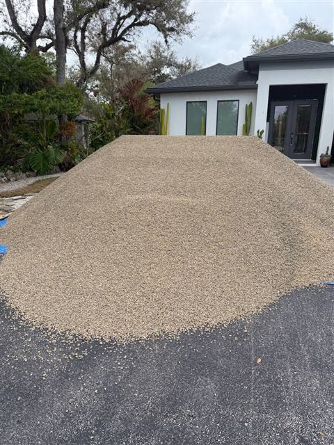 Load of tan gravel delivered onto a residential driveway
