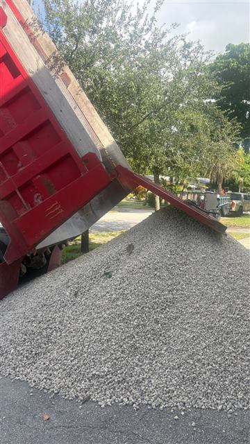 Dump truck unloading gravel on a residential street